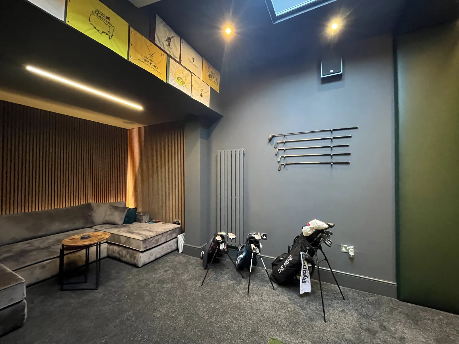 A finished simulator lounge with sofa and golf bags
