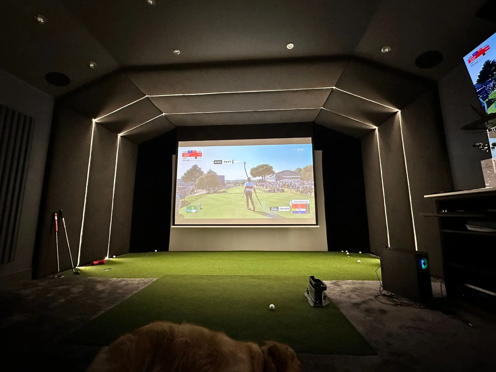 The finished simulator room, with a projected screen, lit surround and turf mat