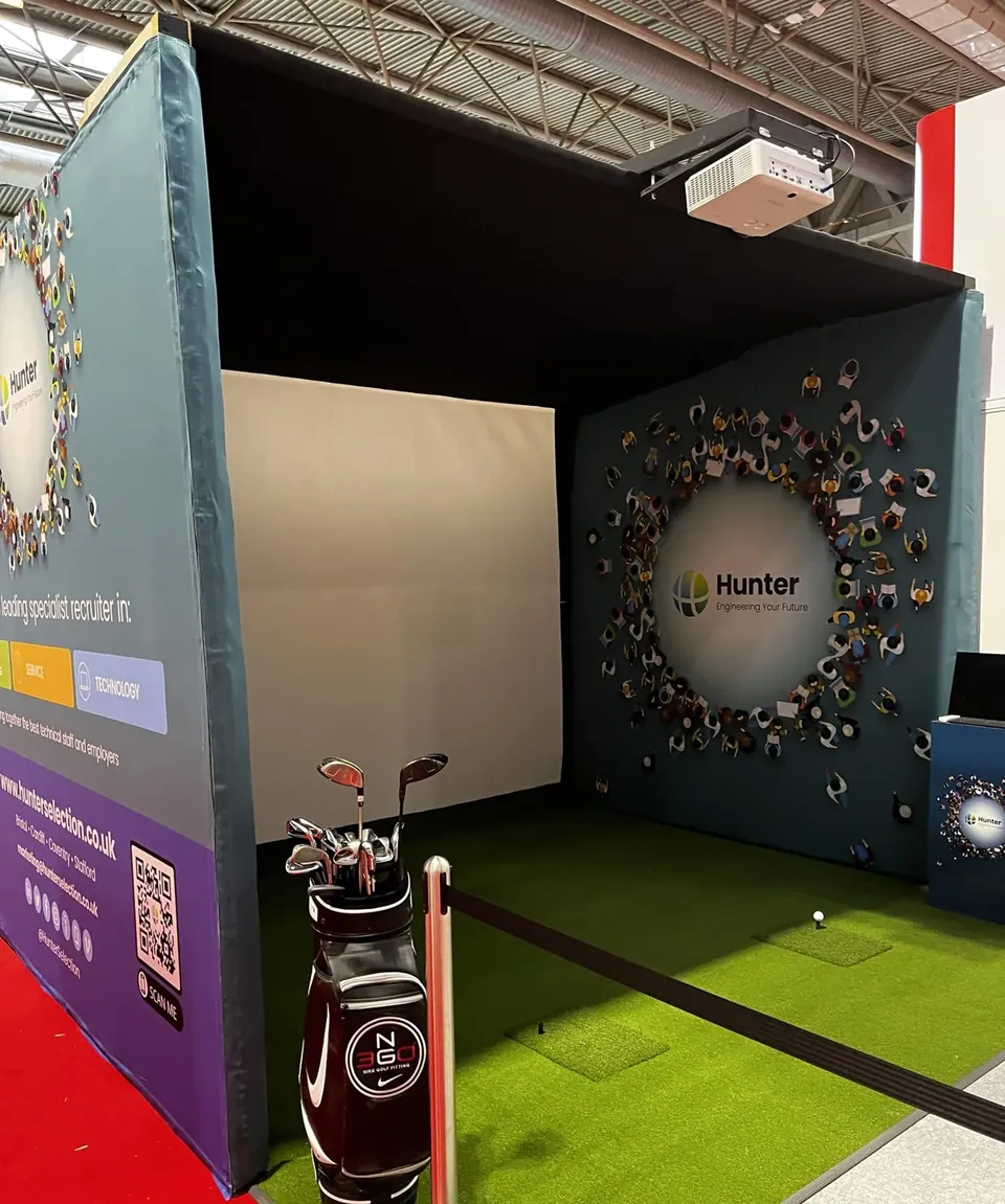 Inside the padded bay: impact screen, ceiling projector, turf and a tee
