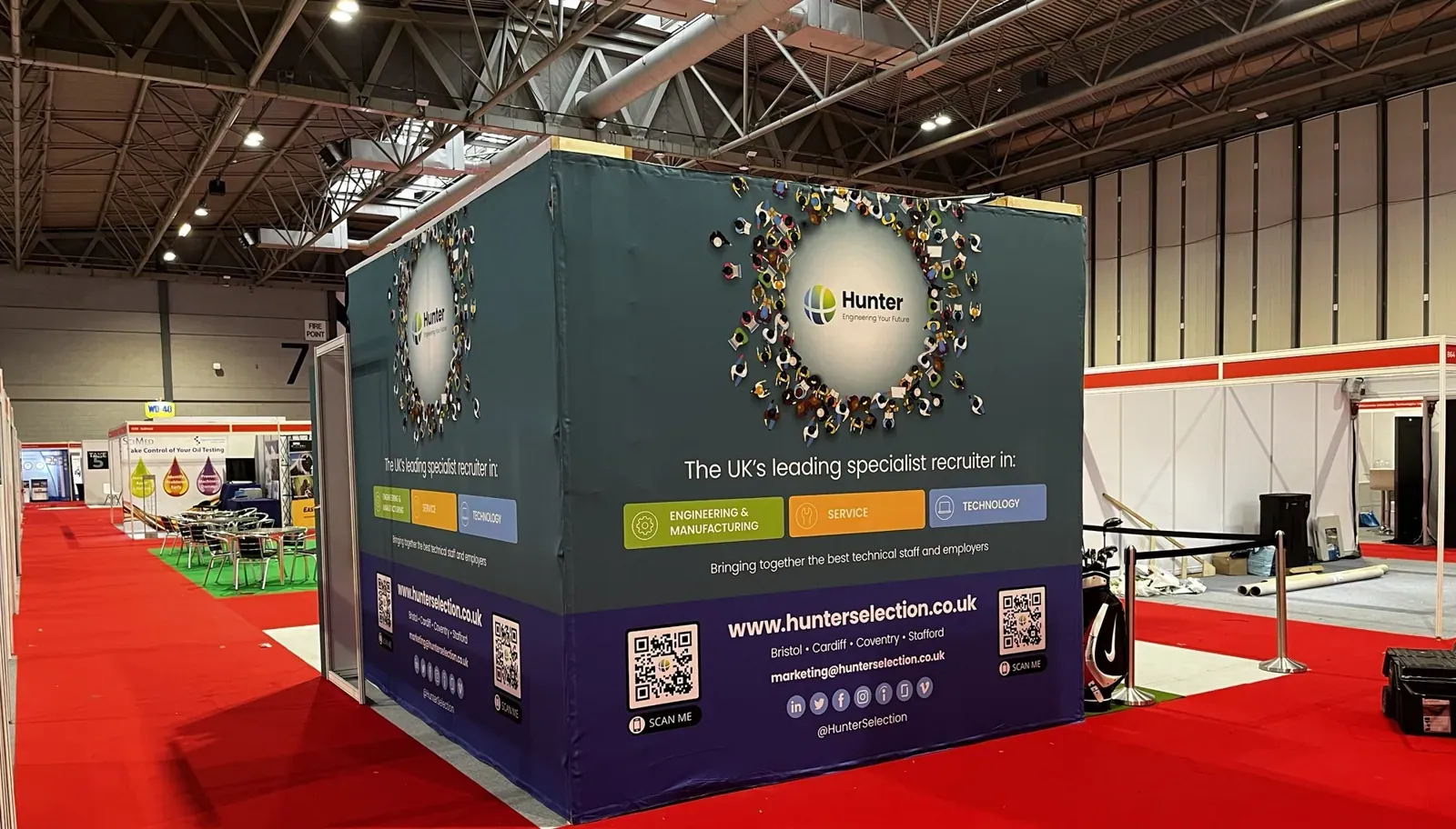 A Strikeclub timber-frame golf bay wrapped in printed fabric, standing in an exhibition hall