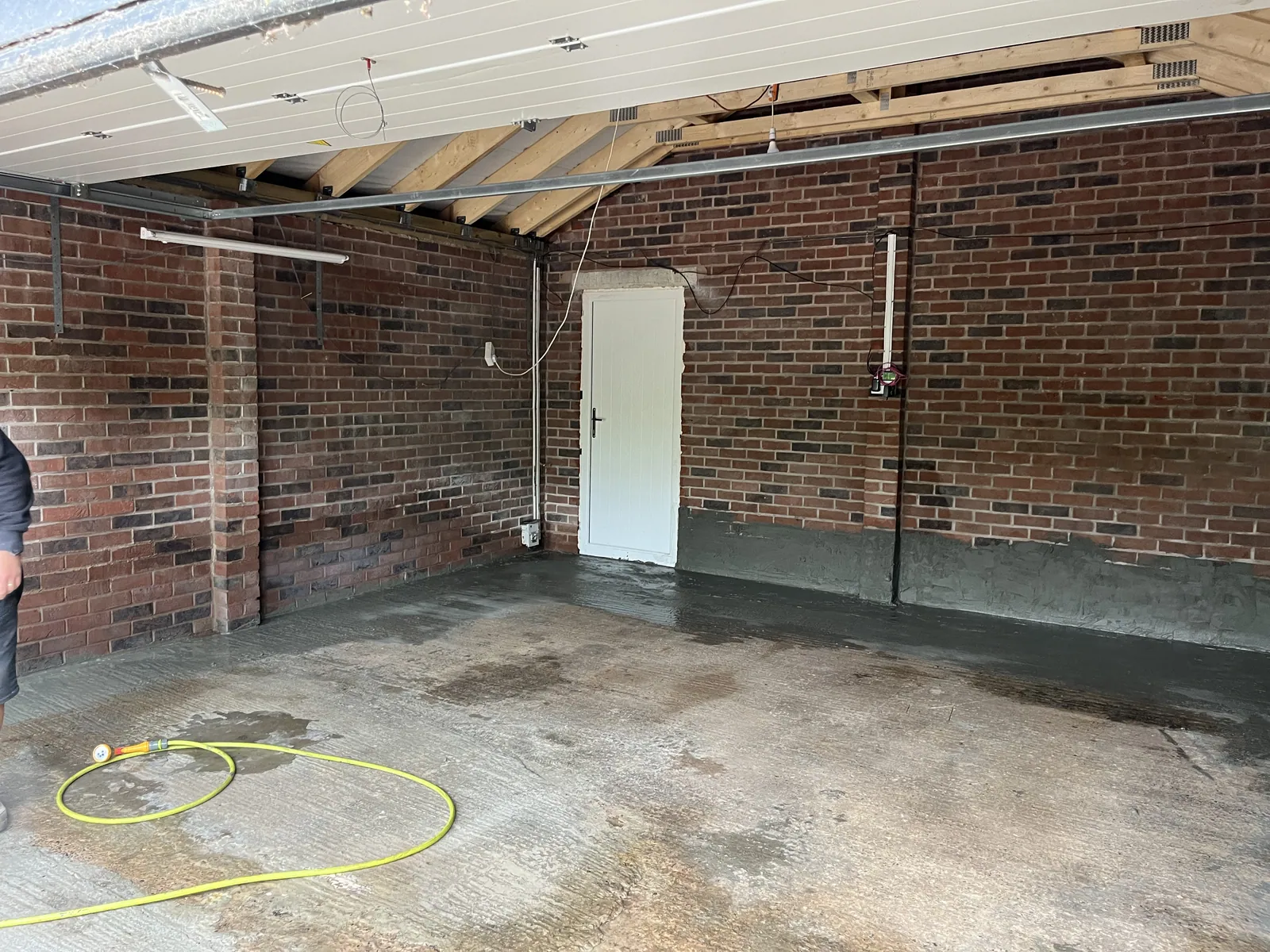 A plain brick garage with a concrete floor before work started