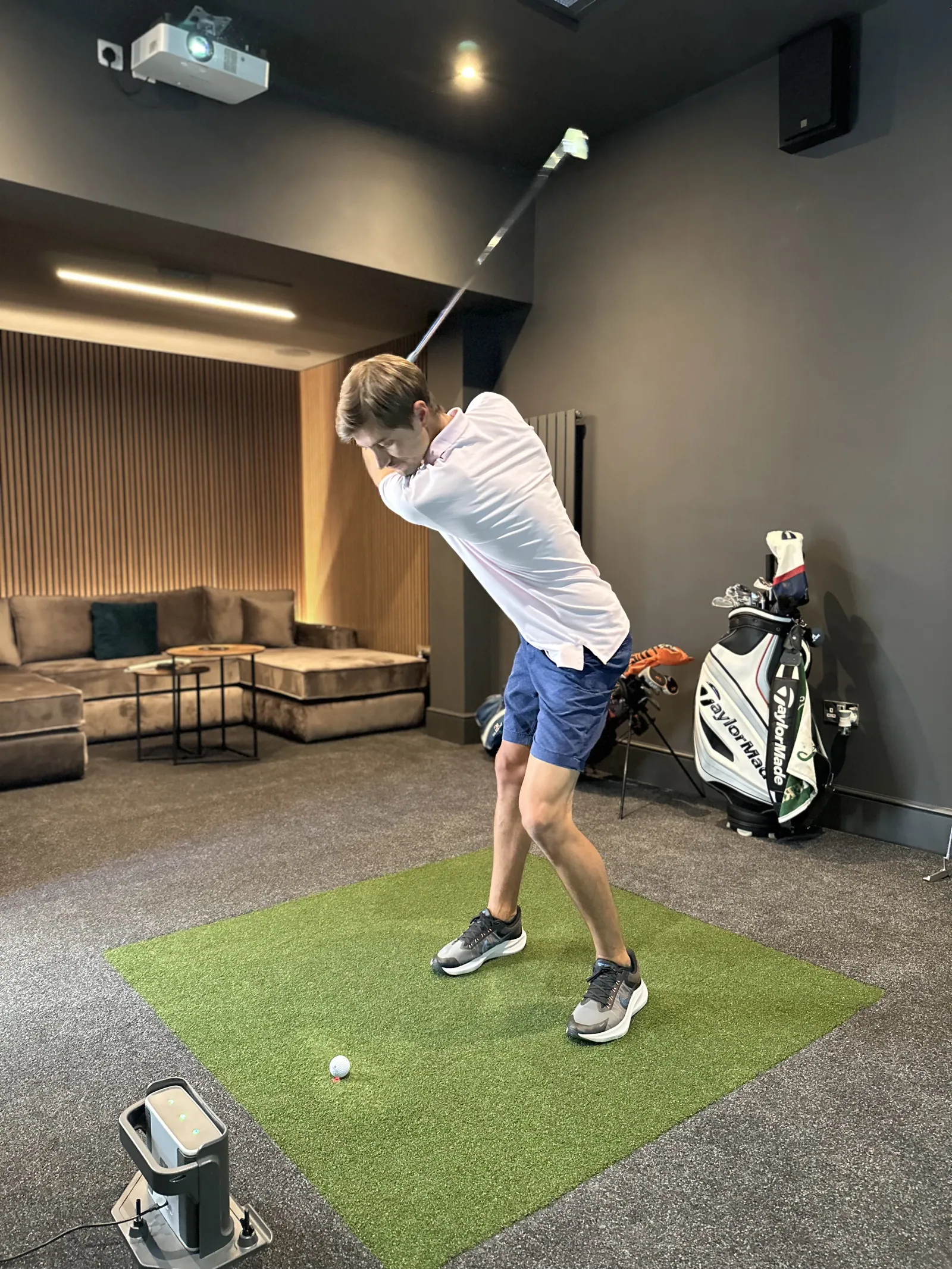 A golfer mid-swing in a Strikeclub simulator