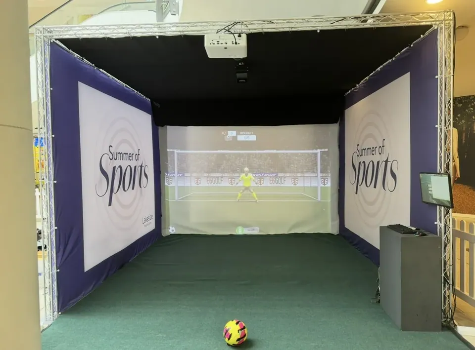 The Strikeclub mobile truss-frame rig set up indoors with a football game on the screen